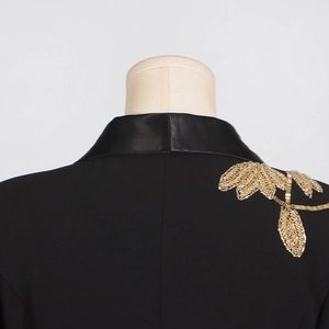 Detail of black blazer featuring satin lapels and intricate gold beaded leaf embroidery