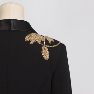 Close-up of golden beaded leaf embroidery on the shoulder of a black blazer jacket