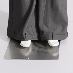 Détail du pantalon large gris foncé montrant l'ourlet replié et la texture du tissu chic