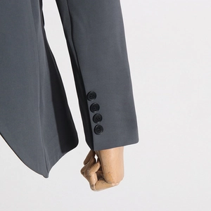 Detail of grey blazer sleeve with four black decorative buttons and smooth fabric texture