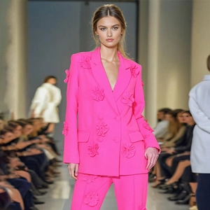 Macro view of bright pink suit with 3D floral appliqués on a runway fashion show