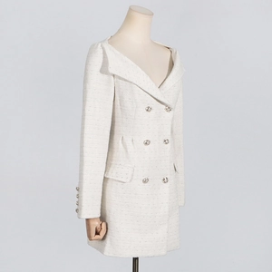 Detailed close-up of white tweed texture and exquisite metal buttons on a long dress