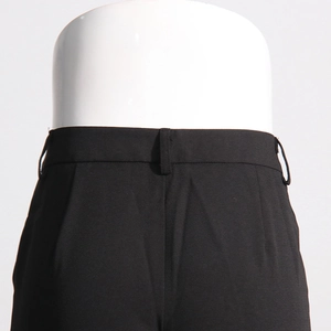 Detail of high-waisted black trousers with belt loops and slim-fit darts on a mannequin