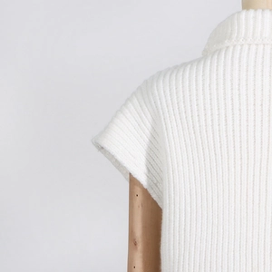 Detailed view of white ribbed knit fabric texture on a wooden mannequin stand