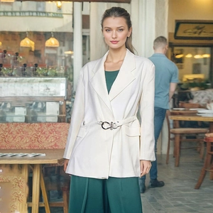Detail of elegant beige blazer featuring slim waist belt and metal horseshoe buckle clasp