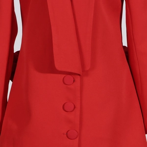 Détail d'un blazer rouge avec trois boutons recouverts de tissu et texture tissée