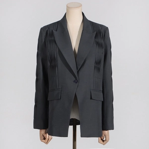 Detailed view of dark grey blazer featuring architectural pleats and single-button closure