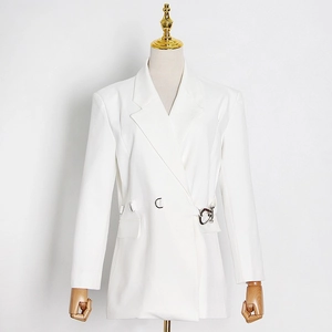 Detail of white slim blazer showing decorative silver horseshoe buckle and waist cinching