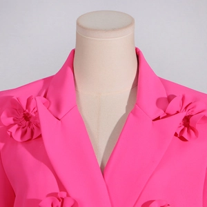 Detail of rose pink blazer lapel featuring a large 3D fabric flower embellishment