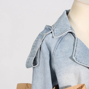 Detail of light blue denim jacket featuring wide lapels and shoulder strap buckle accents