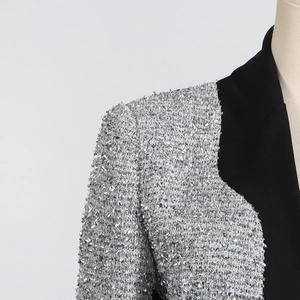 Detail of silver tweed and black fabric contrast stitching on female suit shoulder