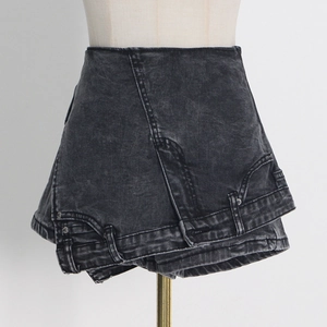 Détail d'une jupe-culotte en jean délavé noir avec taille asymétrique et texture rétro