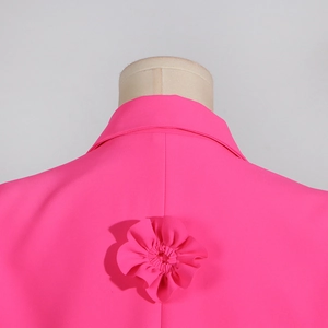 Detailed view of handmade fabric flower applique on the back of a bright pink blazer