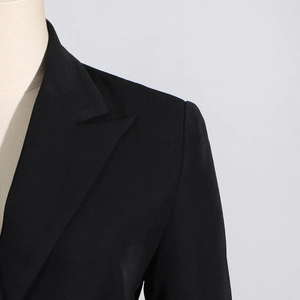 Detail of a slim fit black blazer with peak lapels and structured shoulders for women