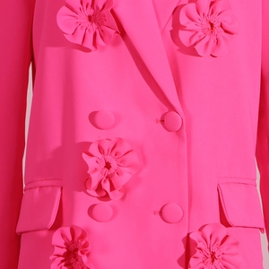 Detailed view of 3D floral appliqués and double-breasted buttons on a magenta blazer