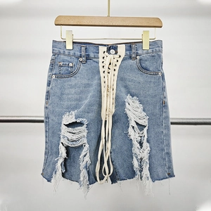 Detail of high waisted denim shorts with crisscross lace-up front and ripped distressed hem