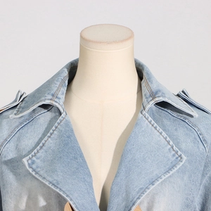 Detailed macro shot of light blue denim jacket lapel collar with decorative shoulder straps