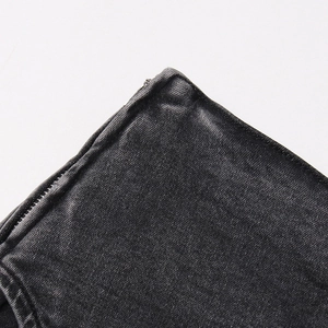 Détail macro de la fermeture éclair latérale et texture du denim sergé sur short gris