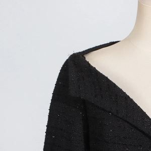 Close-up of black tweed fabric with shimmering sequins and crossover neckline detail