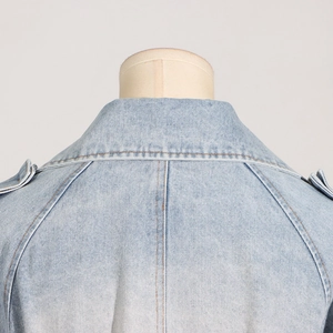 Close-up of light blue denim jacket collar with epaulets and fine stitching details