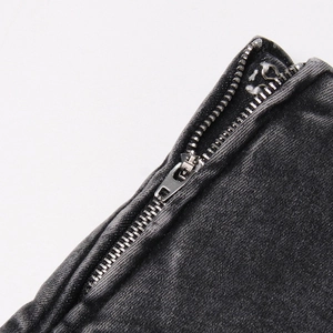 Détail de la fermeture éclair métallique et du crochet sur un short en jean noir