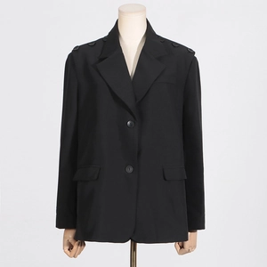 Détail d'un blazer noir cintré avec revers à cran et boutons décoratifs sur l'épaule