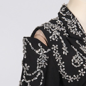 Macro shot of handcrafted rhinestone floral patterns on black cutout shoulder suit jacket
