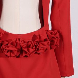 Détail de blazer rouge cintré avec décoration de rose en tissu 3D sur la taille