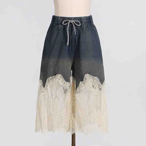 Close-up of high-waist denim shorts featuring exquisite beige lace patchwork and drawstring