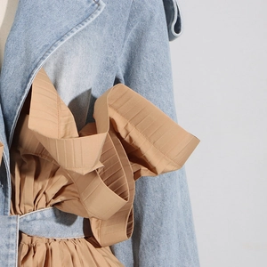 Close-up of contrast denim jacket showing khaki pleated ruffles and stitching detail