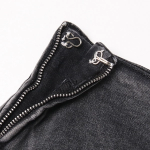 Détail macro de la fermeture à crochet métallique et du zip sur le short en jean