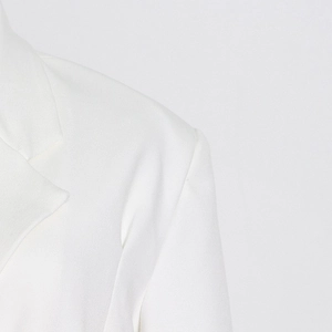 Detail of white blazer showing peak lapels, twill fabric texture and structured shoulders