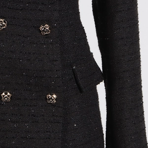 Close-up of black tweed fabric texture with decorative gold buttons and sequin details