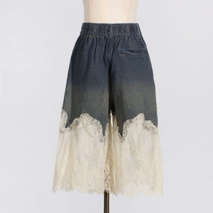 Detail of wide-leg denim shorts featuring elastic waist and intricate lace patchwork trim