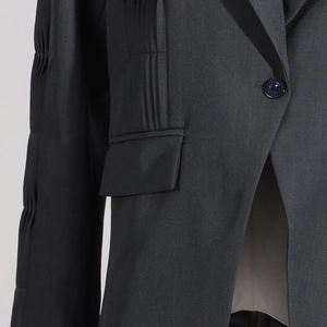 Detail view of stylish pleated sleeve texture and fabric on a dark grey blazer