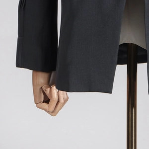Detailed close-up of premium black blazer cuff and hem stitching on wooden mannequin