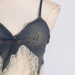 Detailed close-up of a blue denim camisole top with intricate off-white lace stitching