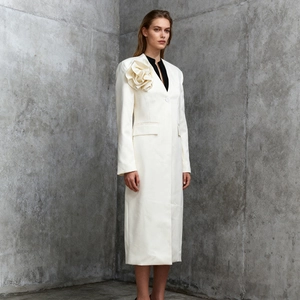 Detail of elegant white long trench coat featuring a 3D floral applique on the shoulder