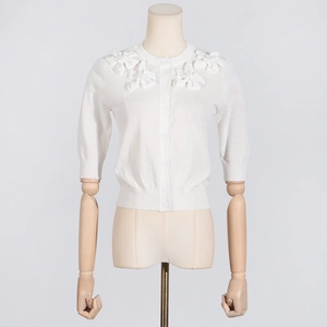 Detail of white knit cardigan with 3D floral appliques and classic round neckline