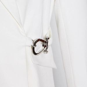Close-up of white blazer fabric with a modern industrial silver metal waist buckle