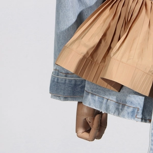Detailed close-up of light blue denim fabric stitched with khaki pleated ruffles and orange seams