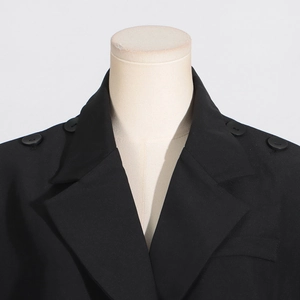 Détail du blazer noir avec revers à encoche et boutons décoratifs sur les épaules