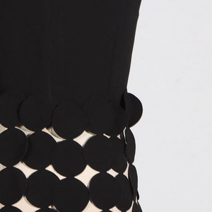 Détail de patchwork de disques noirs et design à franges sur un gilet élégant