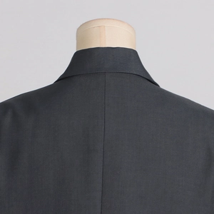 Detail view of the black blazer's tailored back collar and smooth premium fabric texture