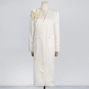Detailed view of handmade floral appliqué on off-white satin trench coat with V-neckline
