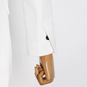 Detailed close-up of white blazer sleeve cuff with twill texture and black button