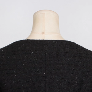 Close-up of black tweed fabric texture with subtle sequins on a round neckline dress