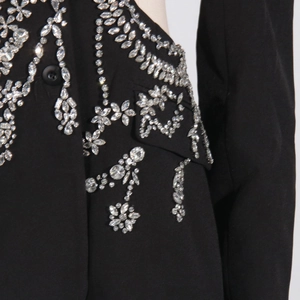 Close-up of sparkling silver rhinestones and floral embroidery on a black blazer