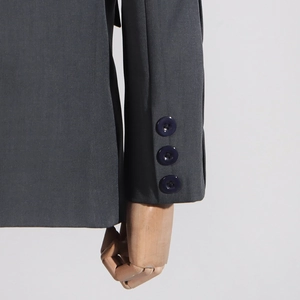 Detailed close-up of three navy buttons on dark grey textured blazer sleeve cuff
