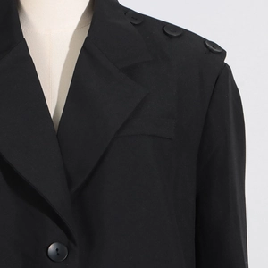 Gros plan détaillé d'un blazer noir avec des boutons sur l'épaule et un col à revers